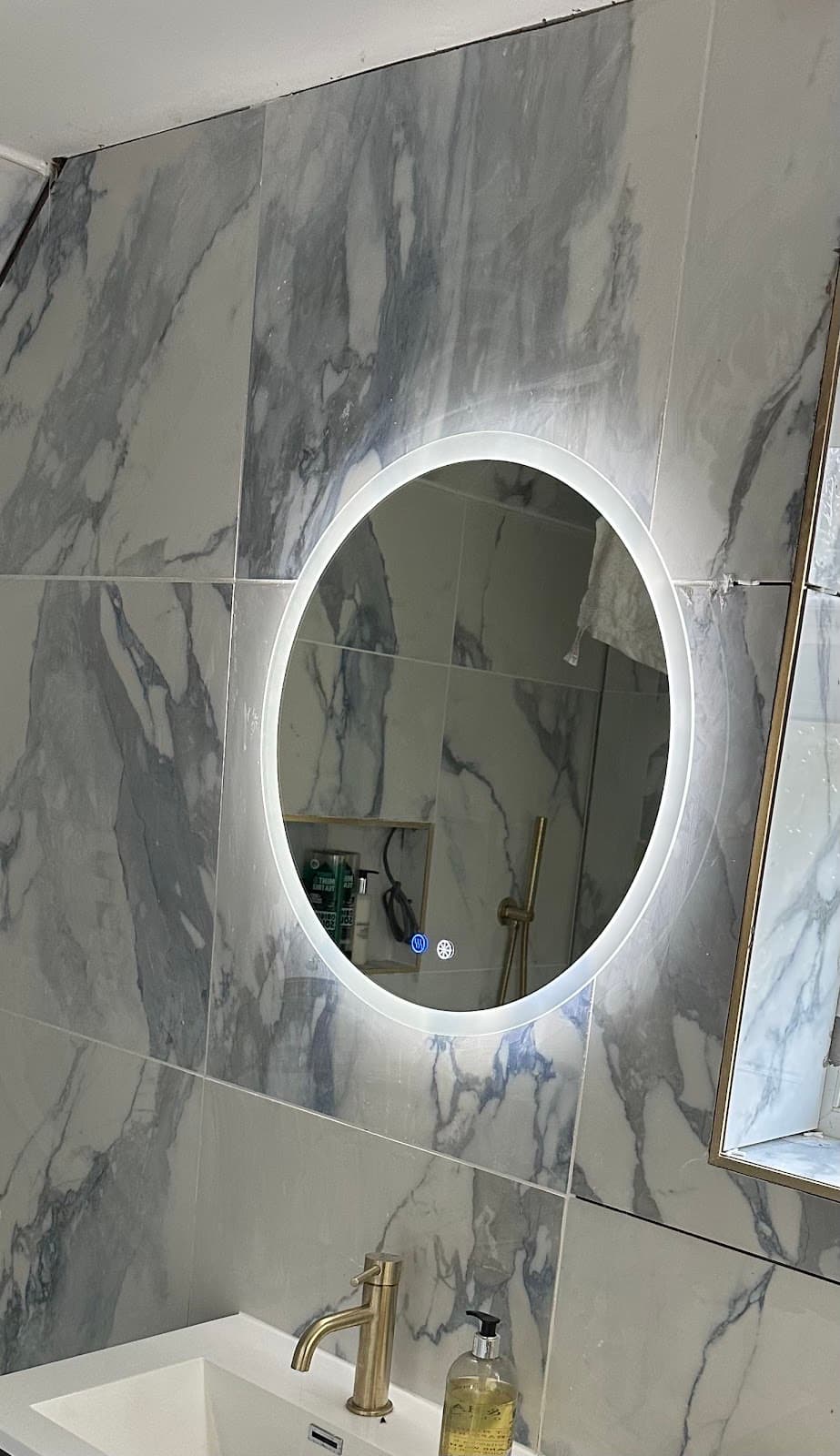 LED backlit bathroom mirror fitted on marble tiling