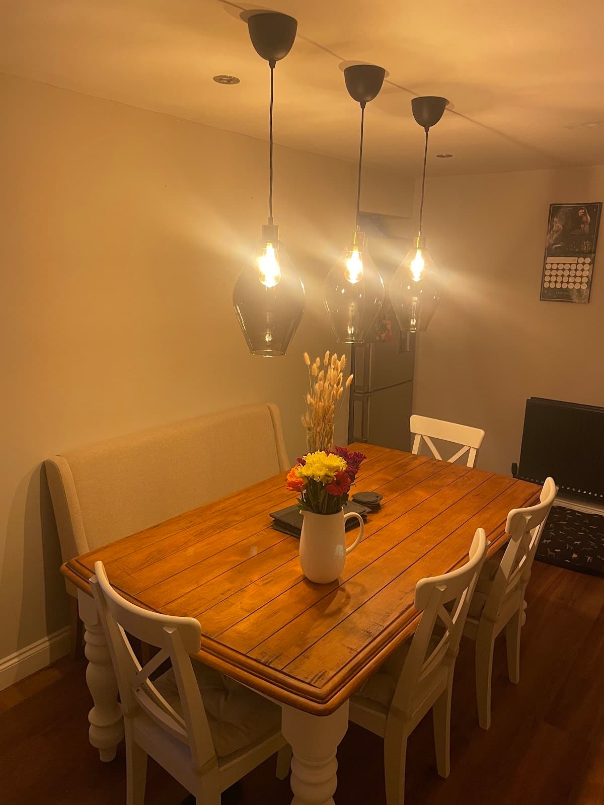 Three glass pendant lights fitted over a dining table