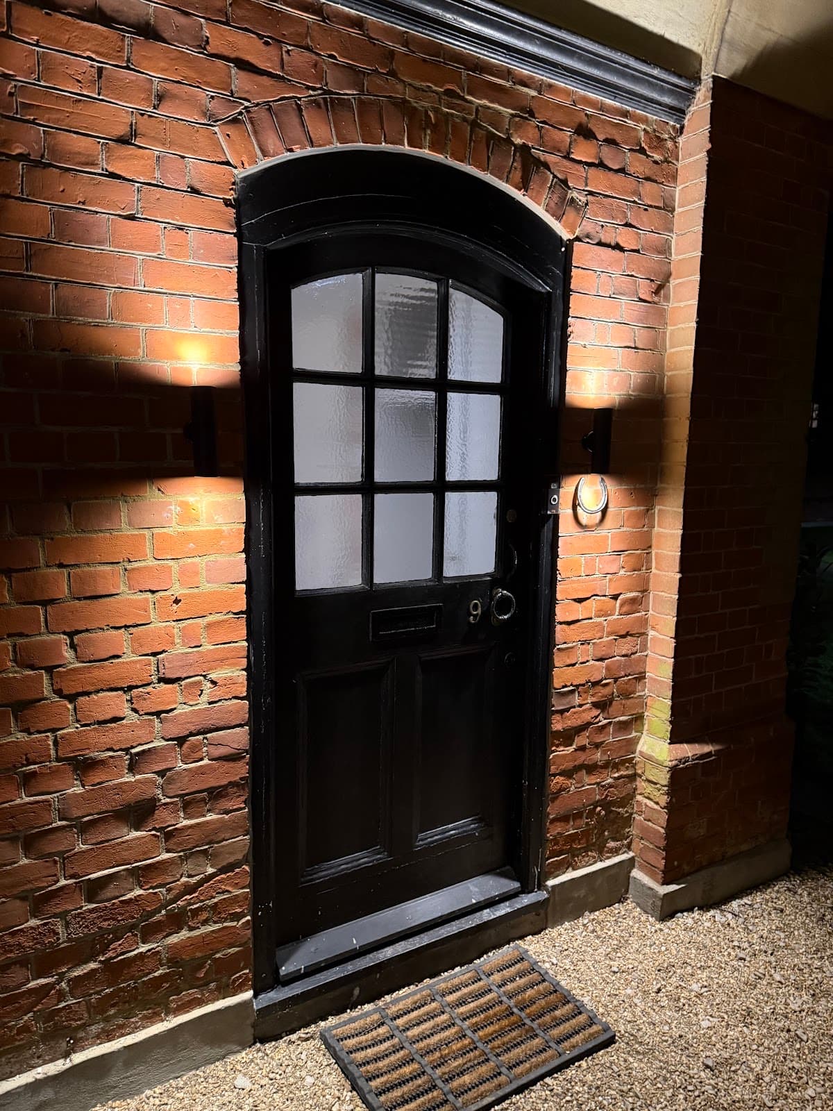Wall lights fitted either side of a front door, lit at night