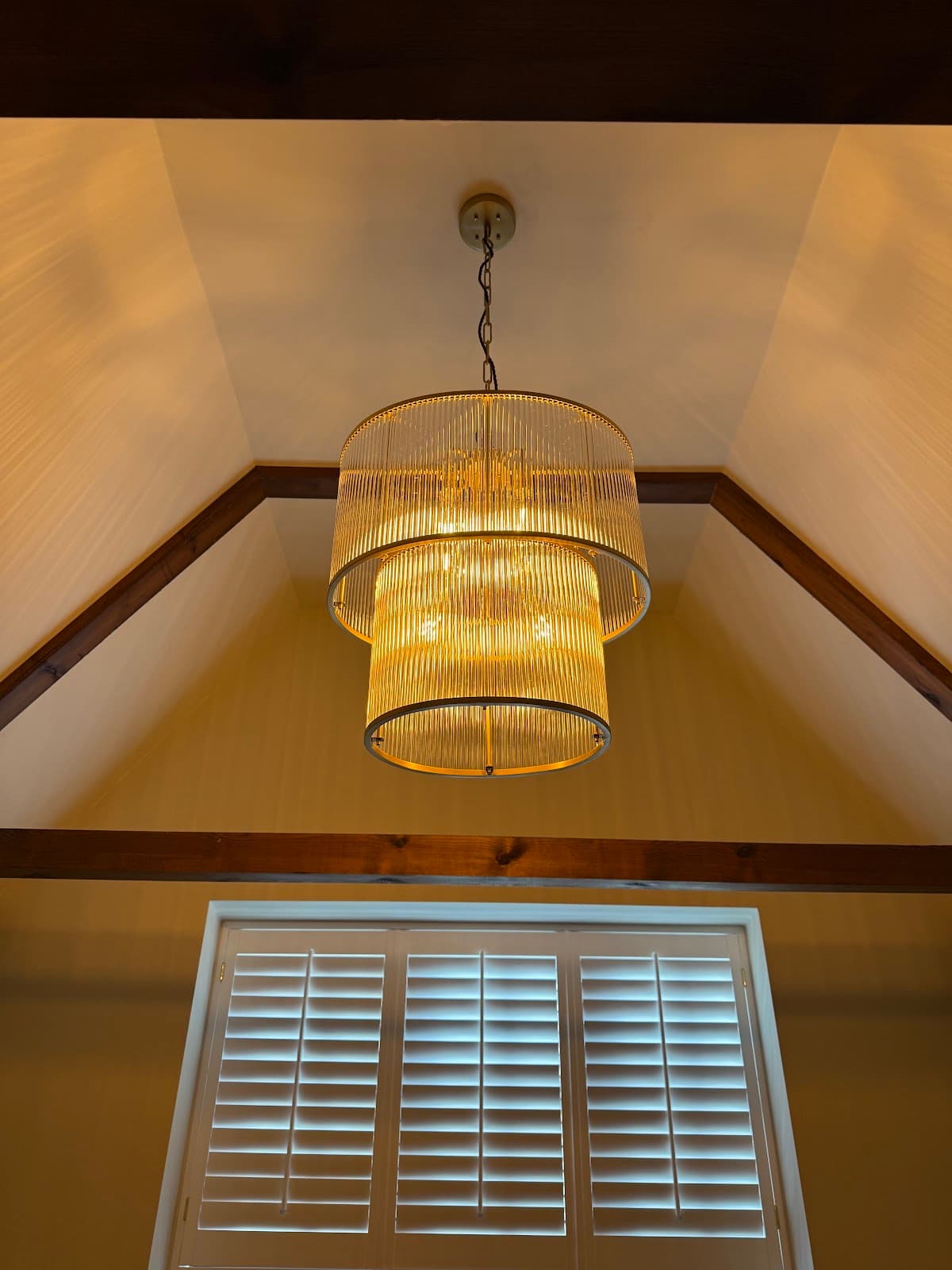 Tiered glass-rod pendant light fitted beside a shuttered window