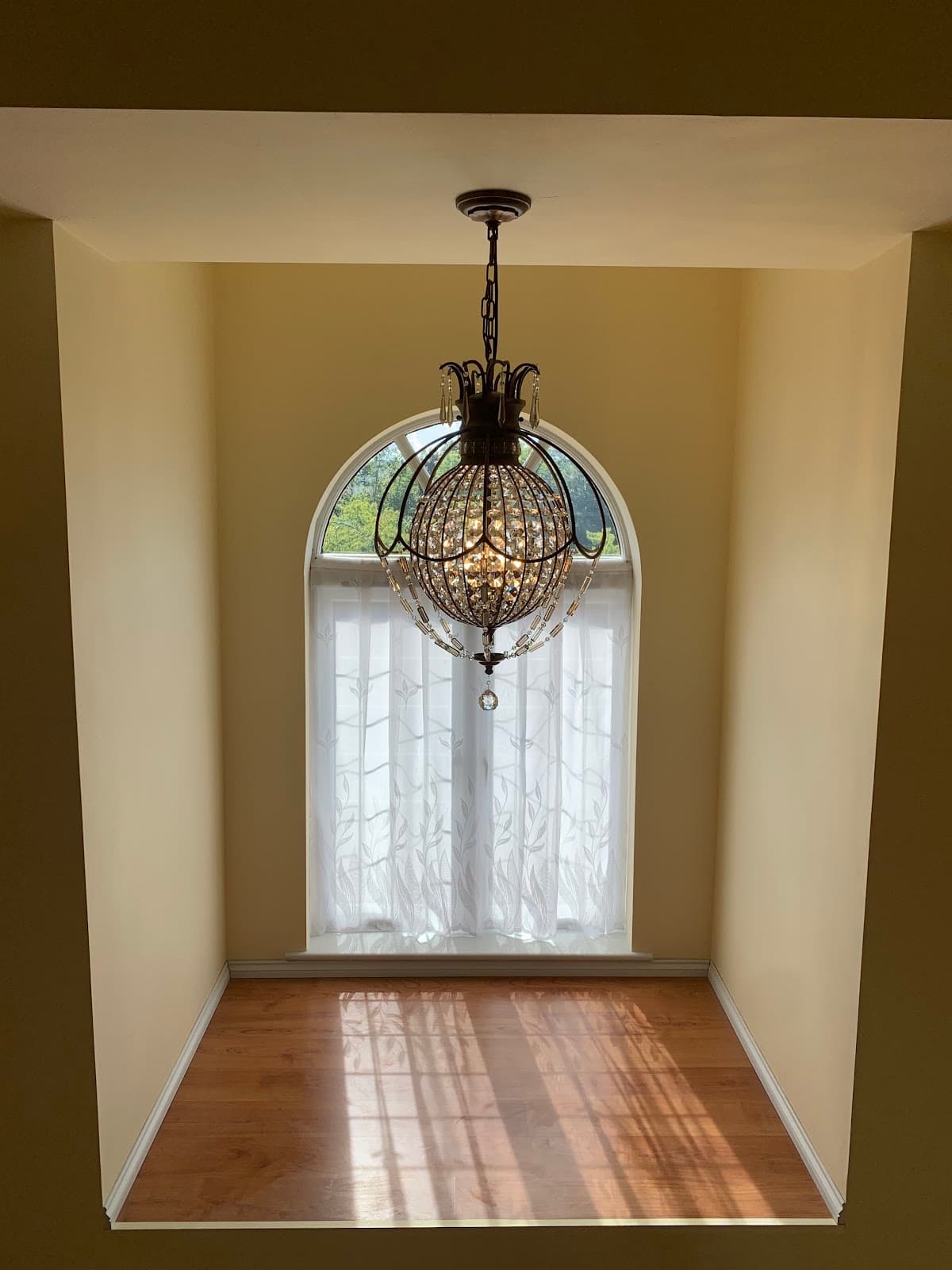 Crystal globe chandelier hung in an arched window alcove