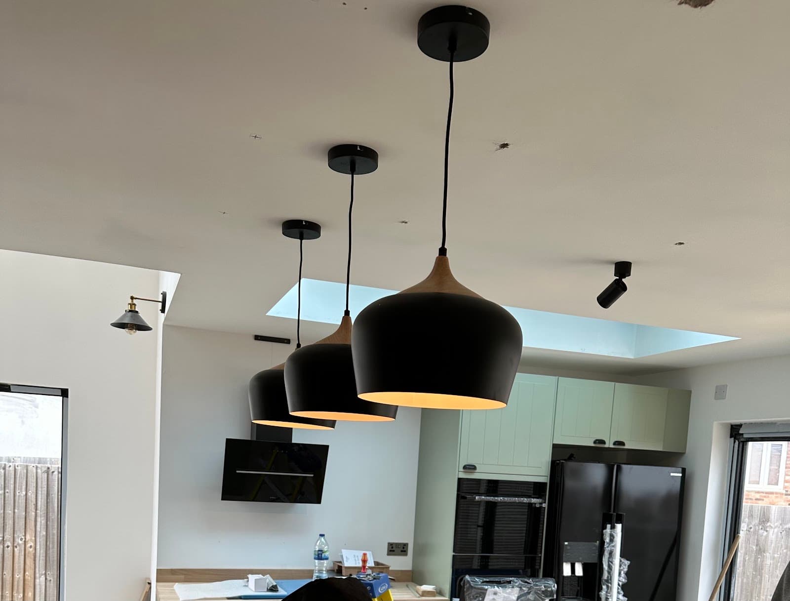 Three black pendant lights fitted over a kitchen island