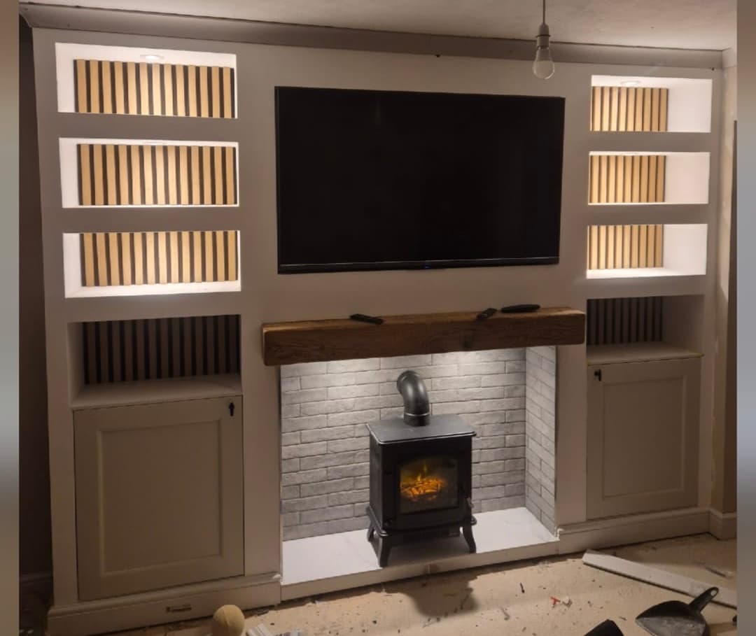Media wall with LED-lit alcoves fitted above a log burner