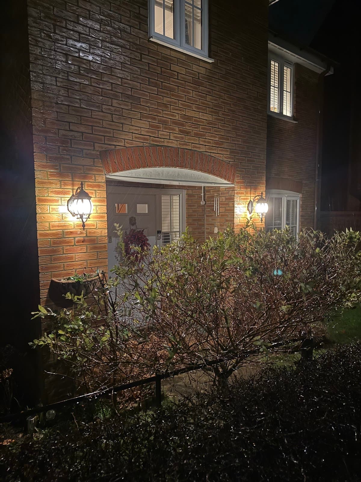 Lantern wall lights fitted either side of a front door at night