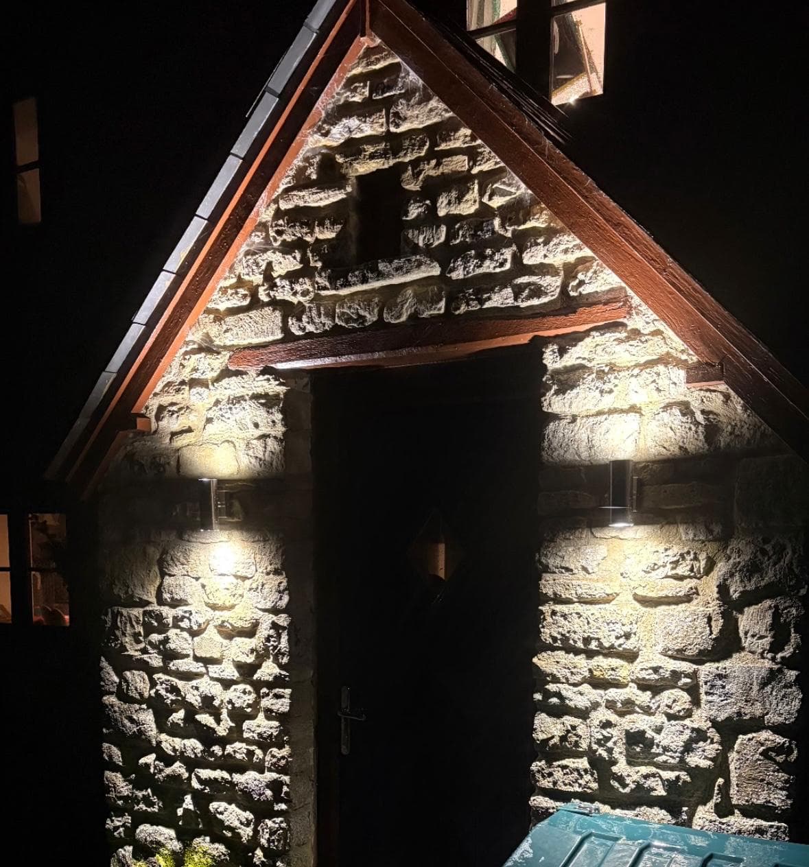 Up-and-down wall lights lighting a stone porch at night